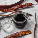 Sirop de caroube dans un pot et graines de caroube